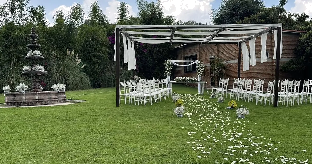 Ceremonia al aire libre bajo pérgola con sillas Chiavari blancas